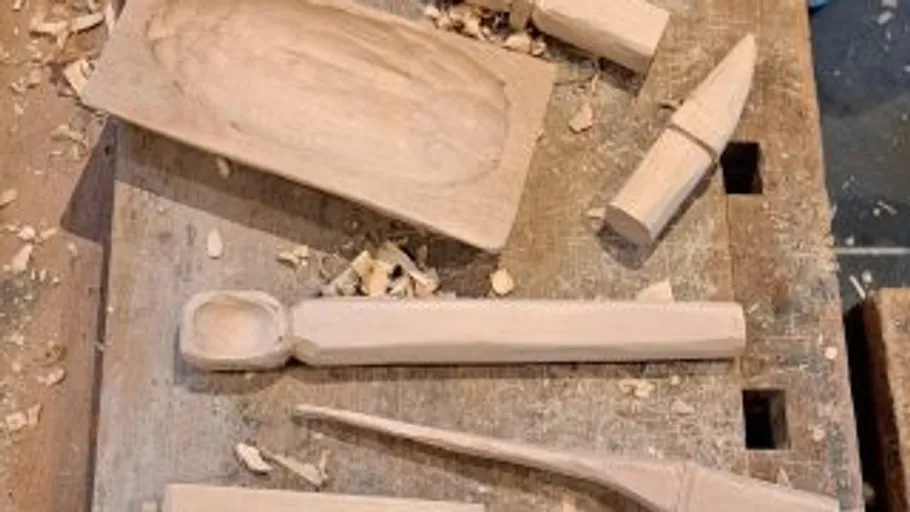 Wooden objects being carved on workbench.
