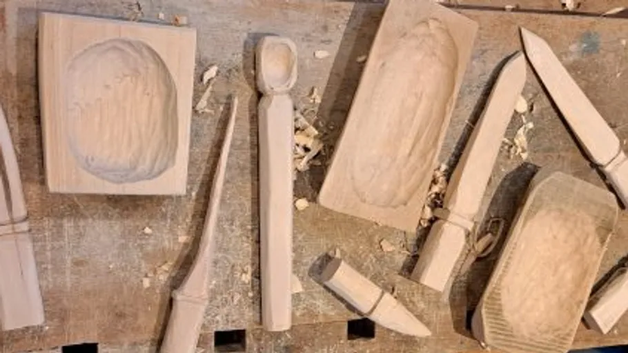 Wooden objects being carved on workbench.