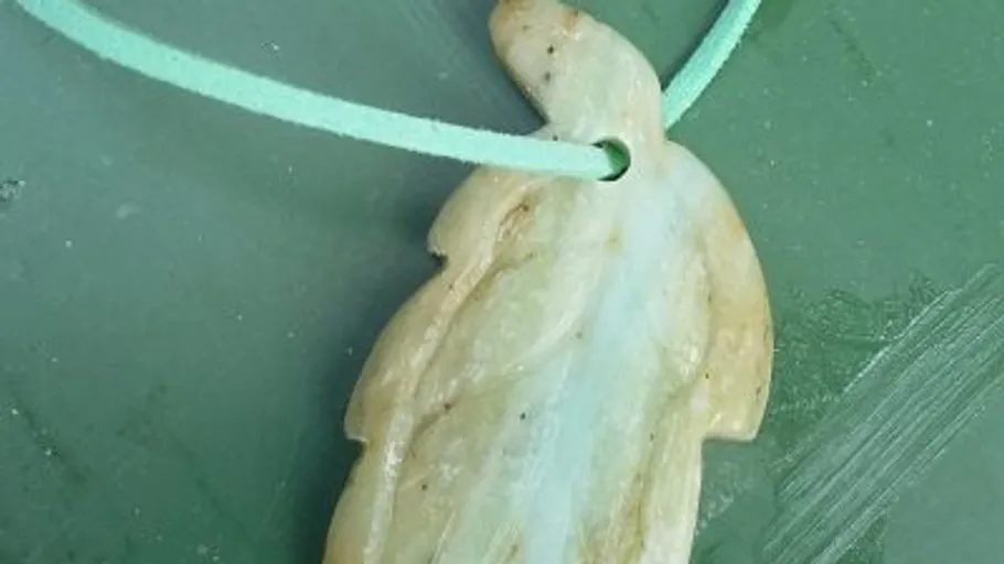 Leaf-shaped pendant on green surface.