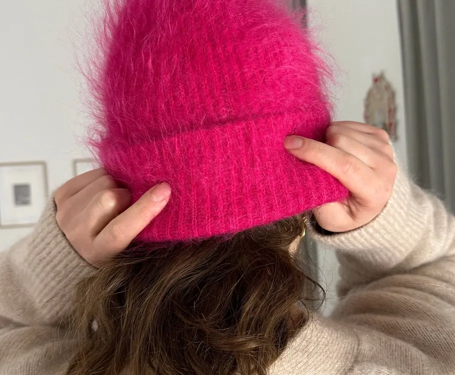 Person passt pinke flauschige Mütze drinnen an.