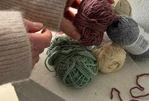 Hands holding yarn over more yarn balls.