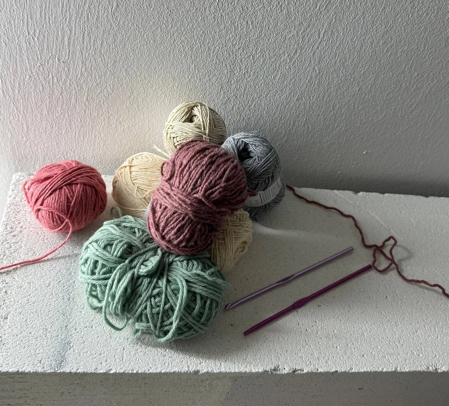 Garnknäuel und Häkelnadeln auf Tisch.