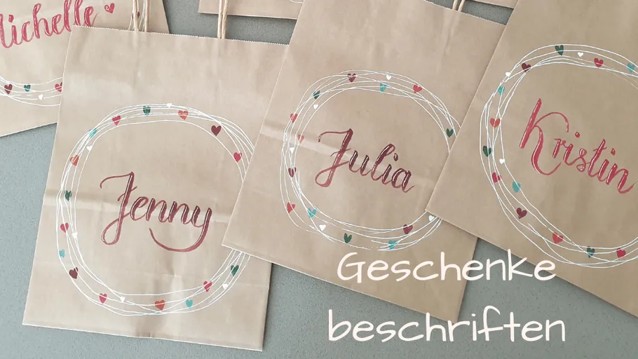 Papiertüten mit Namen auf grauer Fläche.