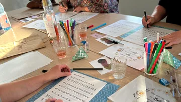 People practicing calligraphy at a table.