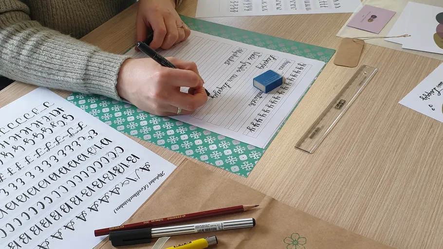 Person übt Kalligraphie an einem Tisch.