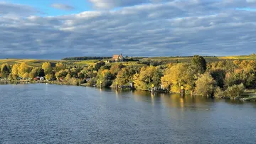 Fluss fließt neben herbstfarbenen Bäumen und Hügeln.