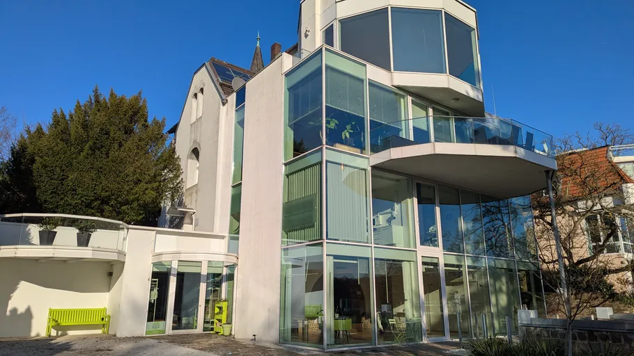 Modern glass house with blue sky backdrop.