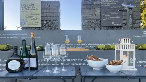 Wine bottles and glasses on outdoor table.