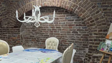 Brick room with chandelier and table.