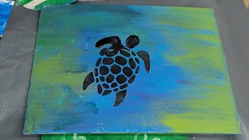 Black turtle painted on blue-green canvas.