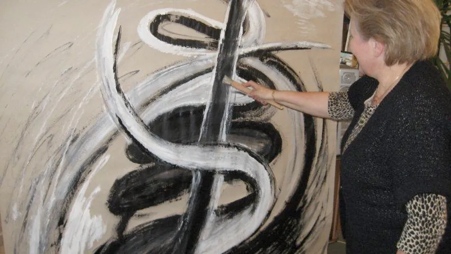 Woman painting abstract design on canvas.