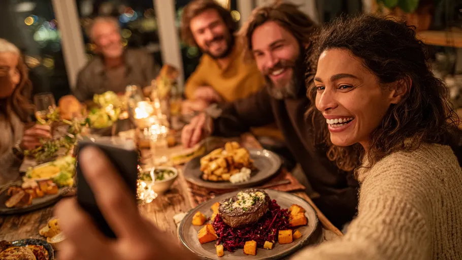 People taking selfie at festive dinner table.