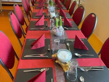 Tisch gedeckt mit roten Servietten in einem festlichen Raum.