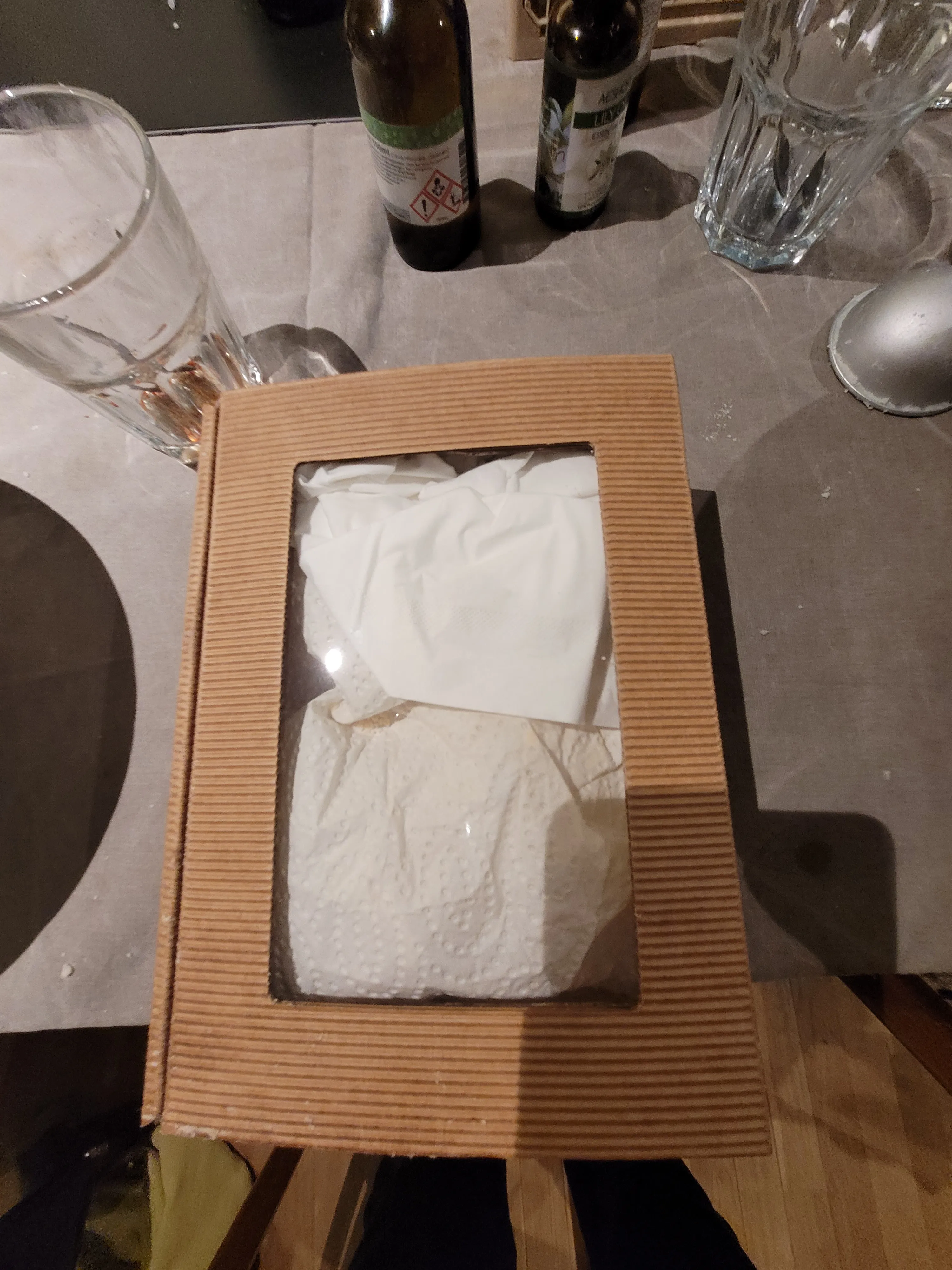 Box with tissues and drinks on table.