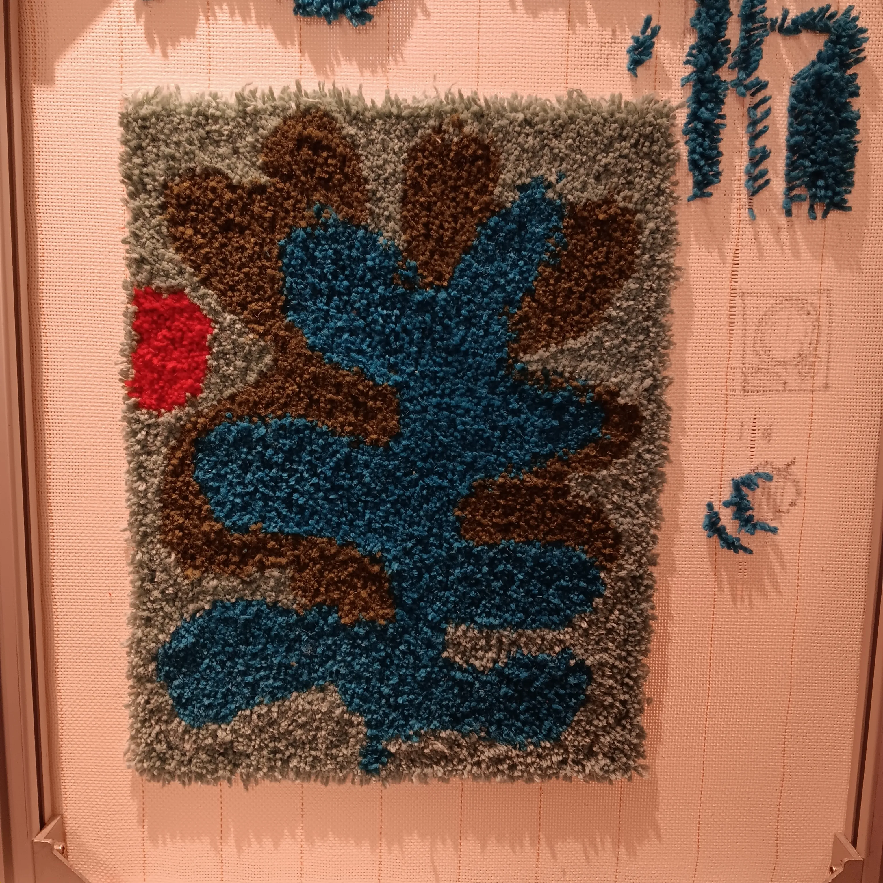 Bunter abstrakter Teppich an Wand hängend.