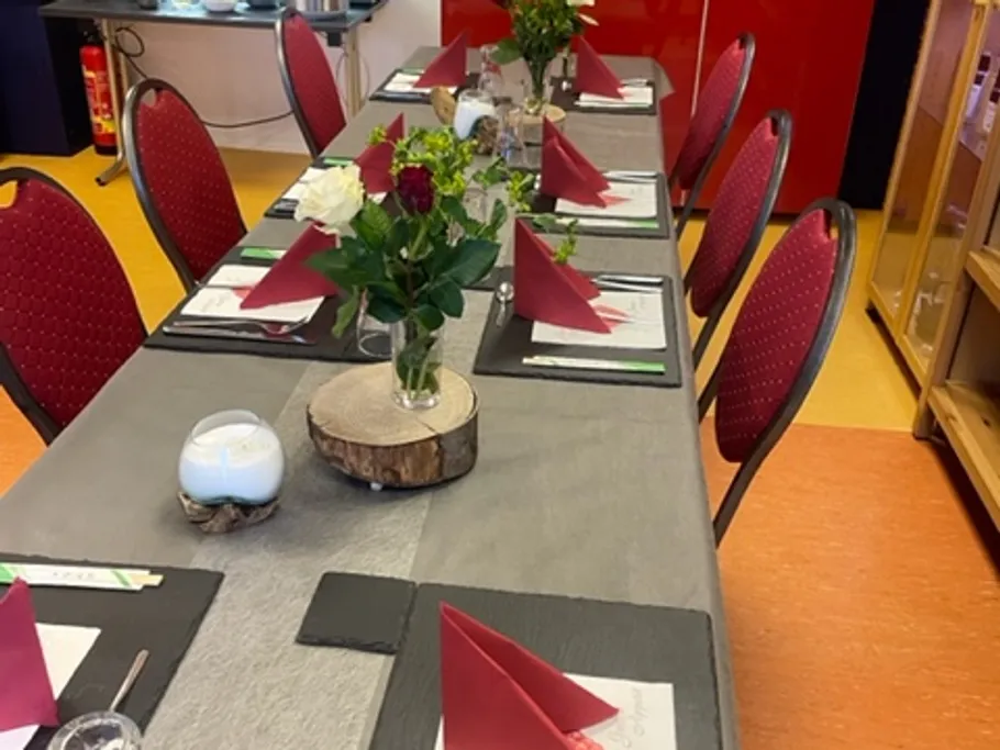 Tisch dekoriert mit Blumen und Servietten in einem Raum.