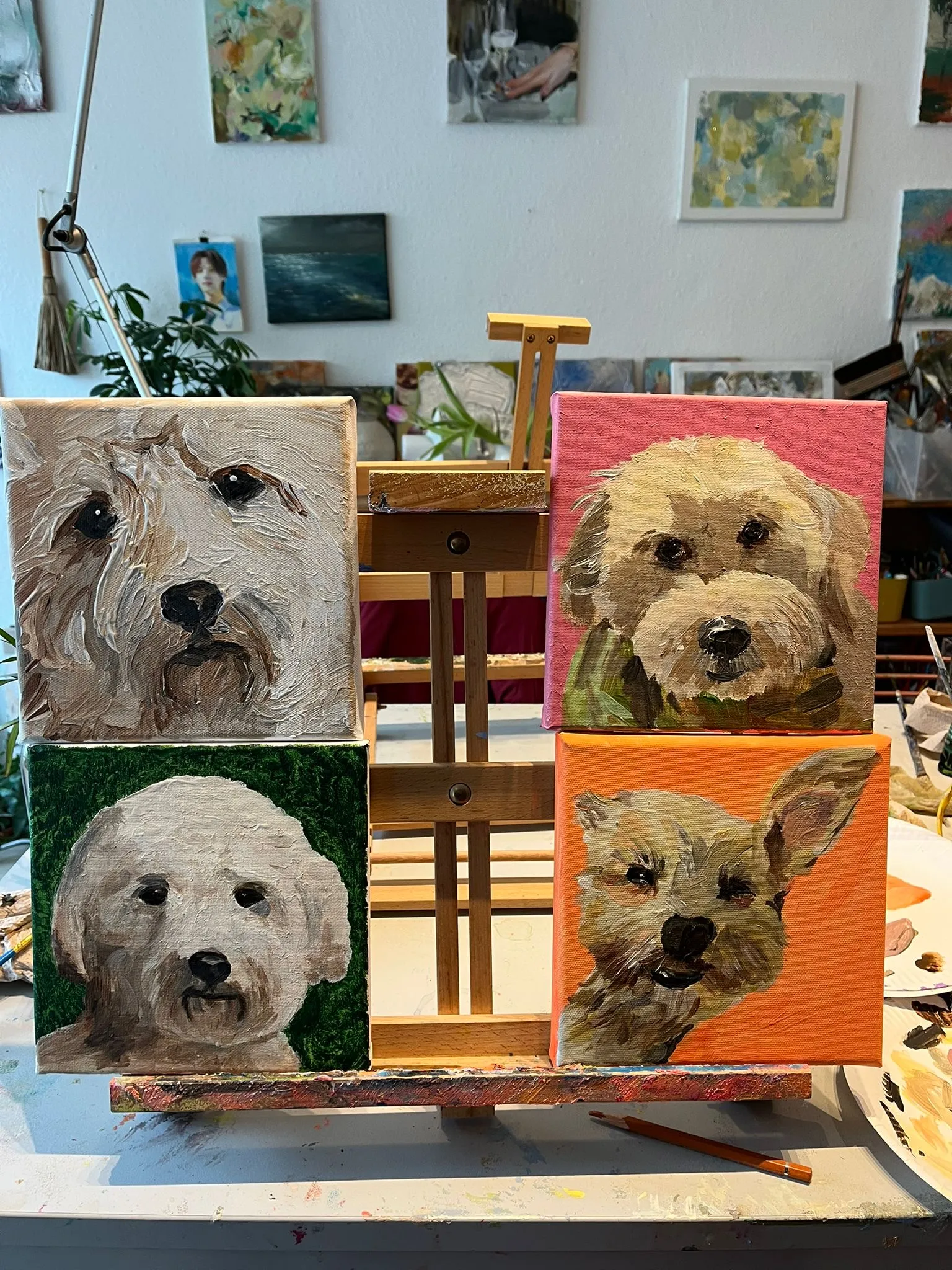 Four dog portraits on an easel in studio.