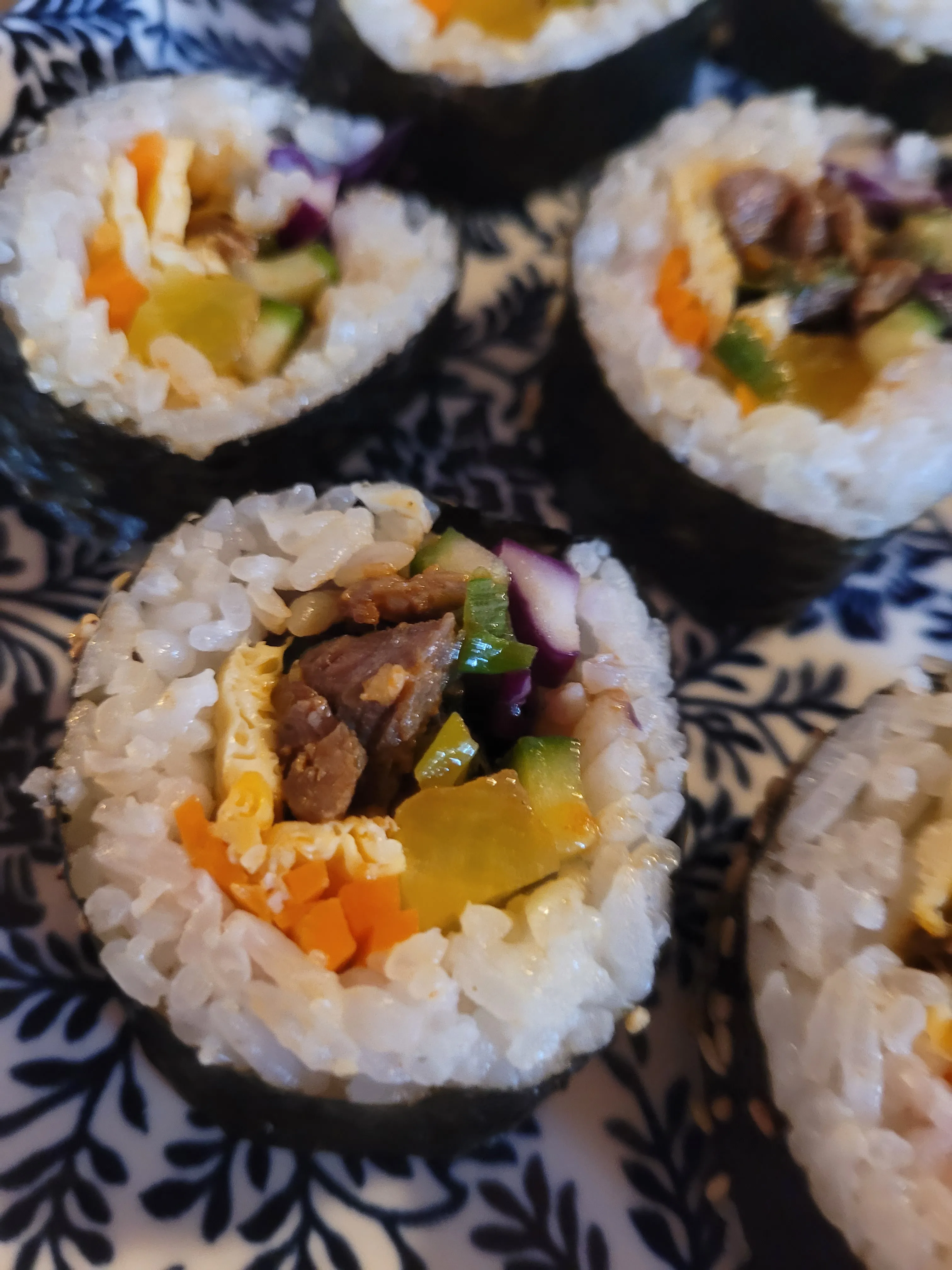Sliced sushi on decorative blue plate.