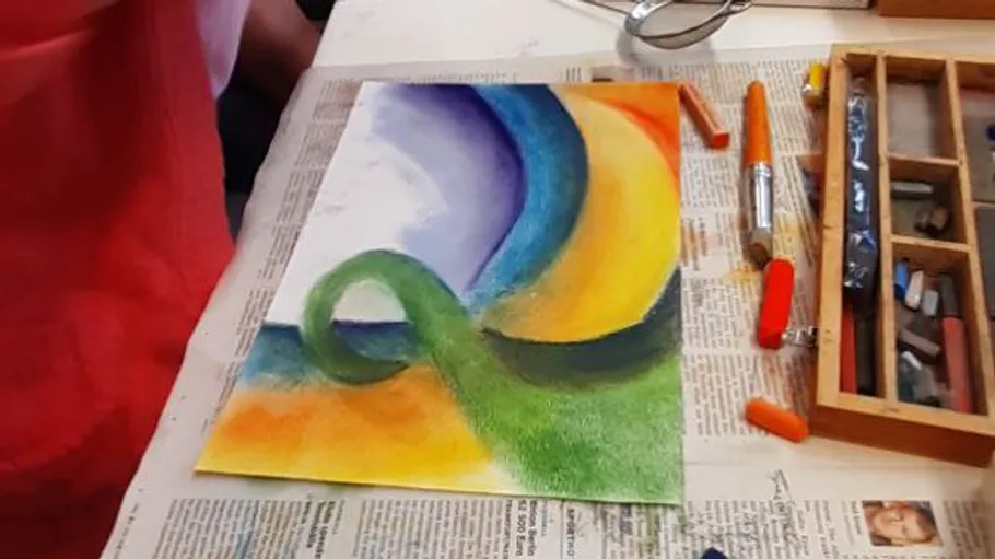 Buntes abstraktes Bild auf zeitungsgedecktem Tisch.