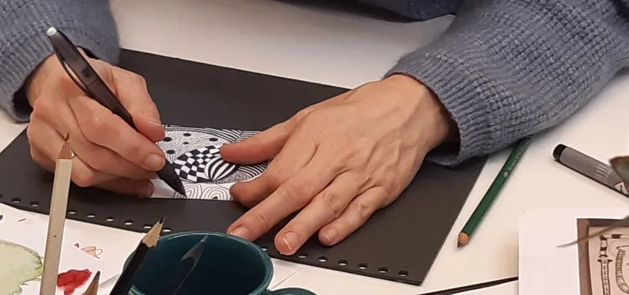 Hände zeichnen komplexes Muster auf Papier.