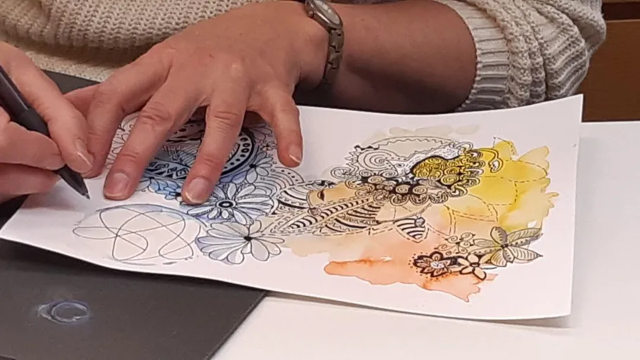 Person drawing floral design on paper.