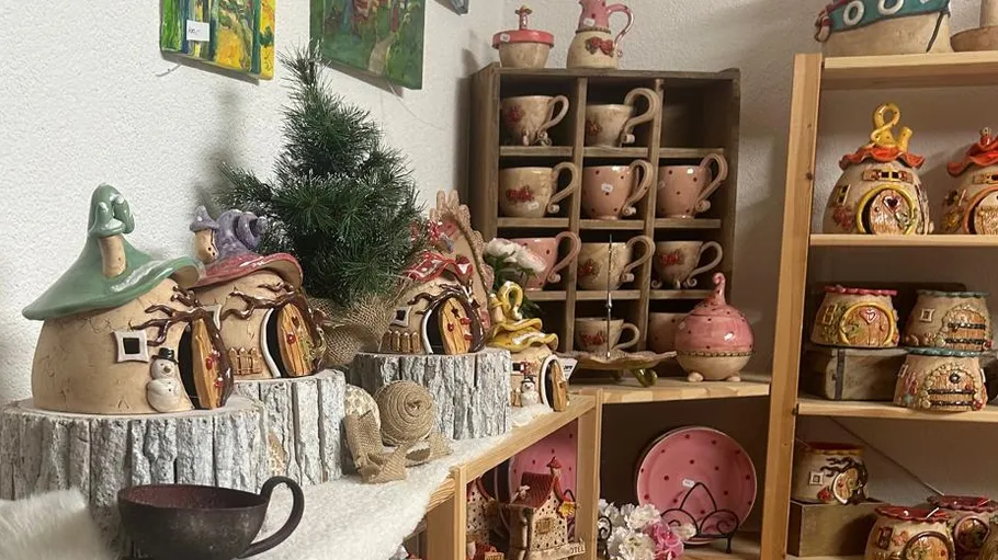 Ceramic fairy houses displayed on wooden shelves.