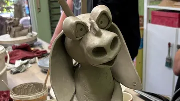 Clay sculpture of donkey on workshop table.