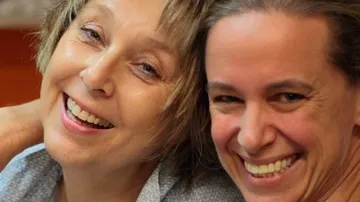 Zwei lächelnde Frauen nah beieinander drinnen.