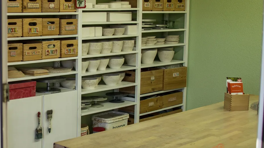 Pottery studio shelves with various ceramics.