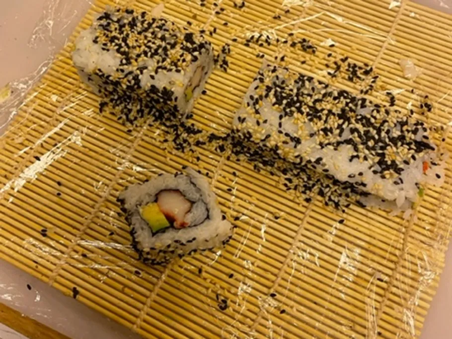 Leftover sushi is lying on a bamboo mat, incomplete.