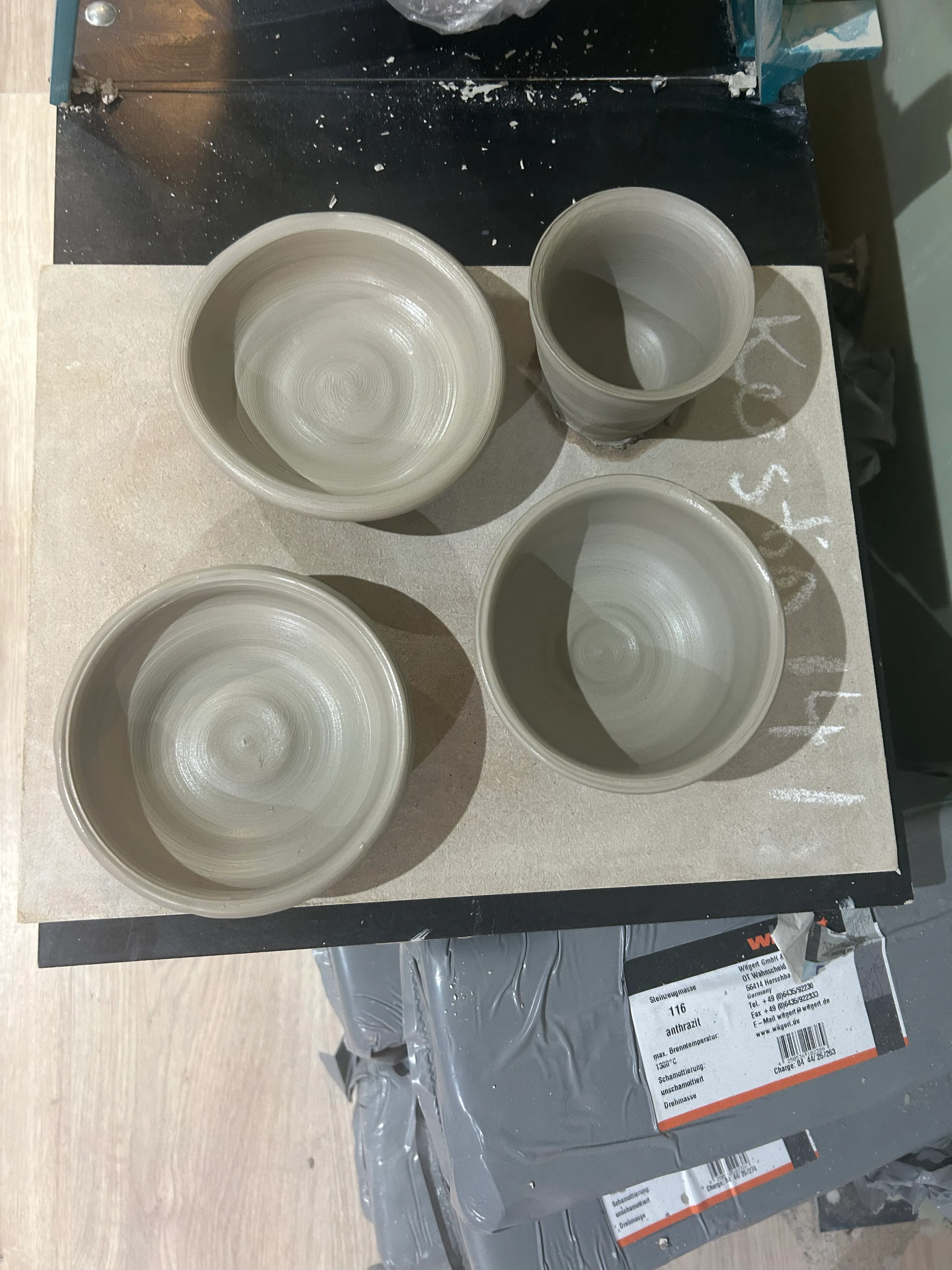 Four clay pots on wooden board.