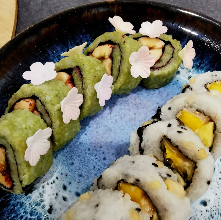 Colorful sushi rolls on a ceramic plate.
