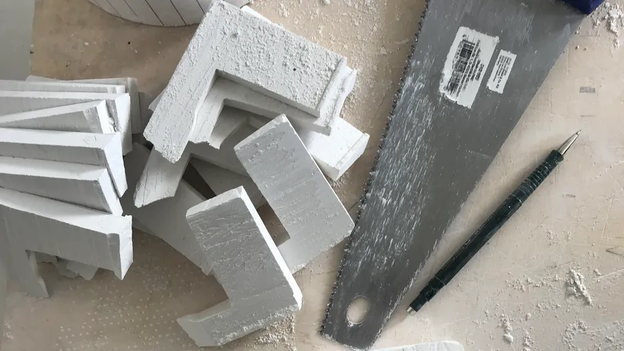 Weiße Schaumstücke mit Säge auf Tisch geschnitten.