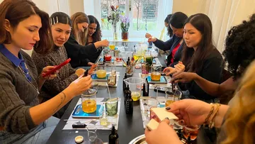 Menschen basteln Kerzen bei einem Tisch-Workshop.