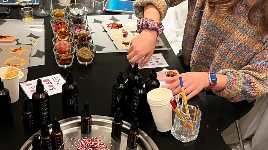 Person crafts perfumes with various ingredients on table.