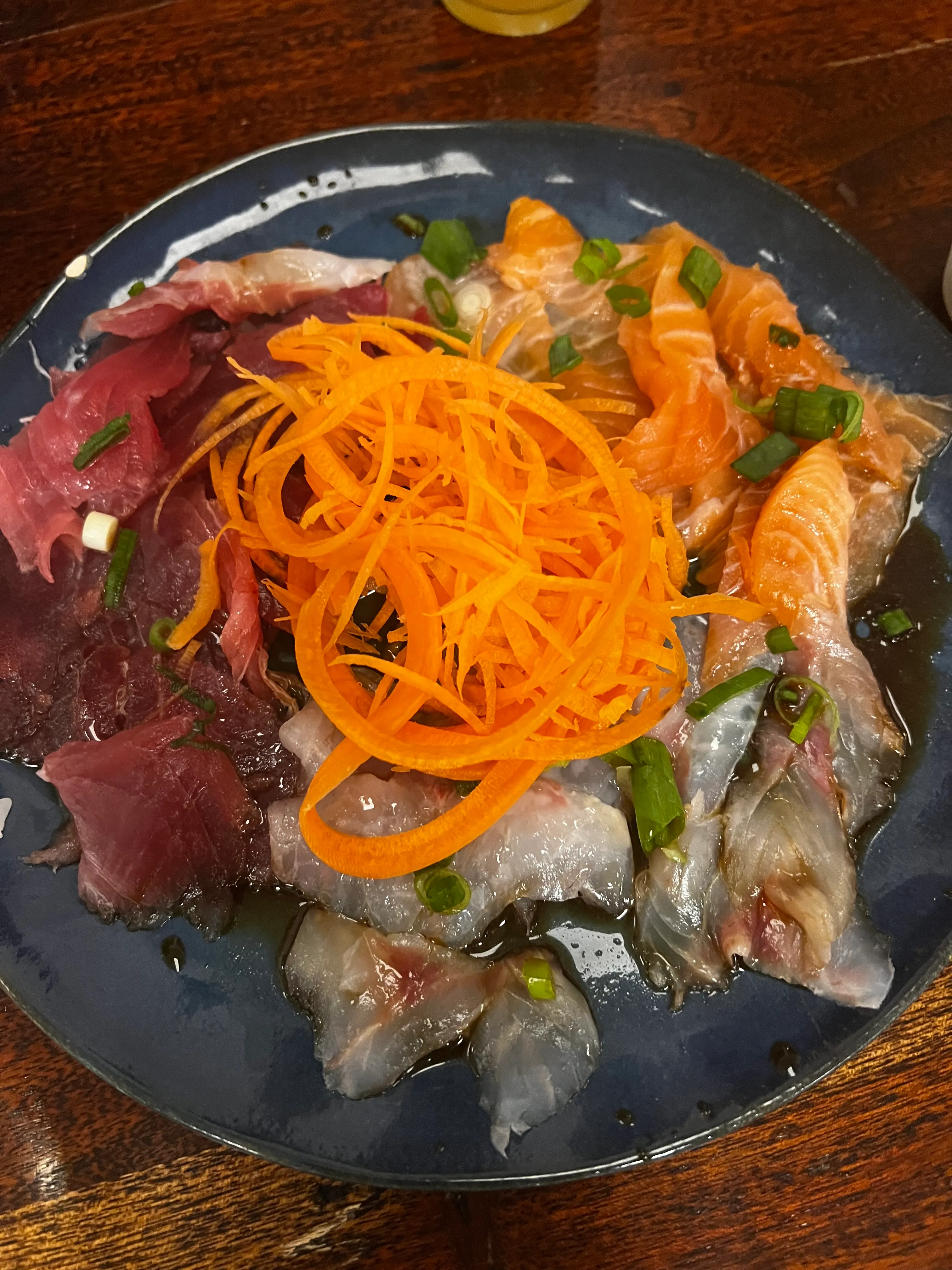 Sashimi assorted on plate, garnished with carrots.