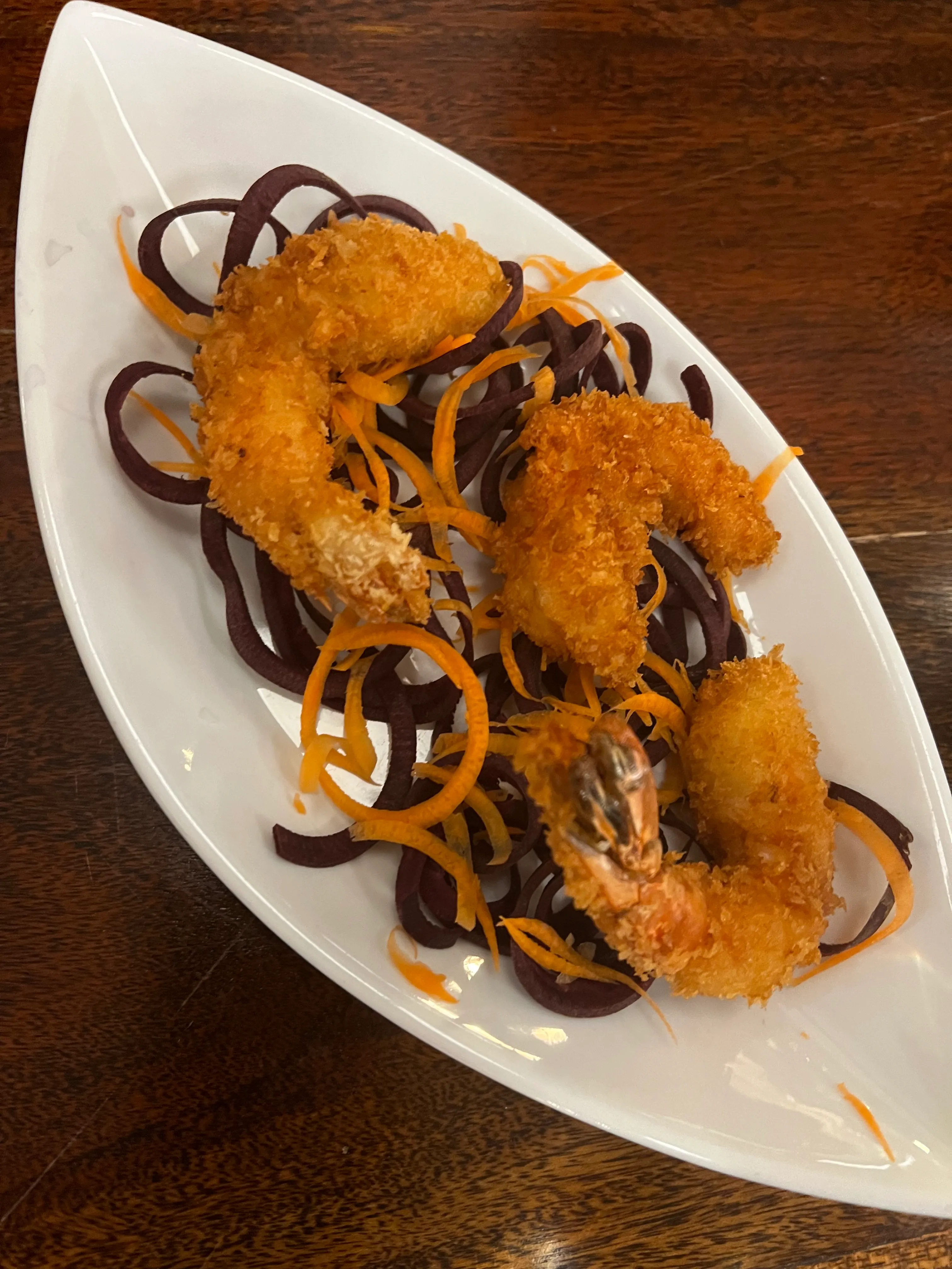 Fried shrimp on noodles in white dish.
