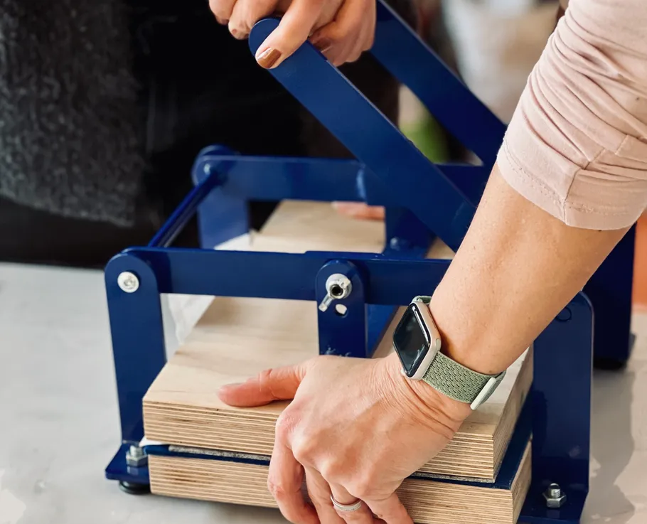 Person pressing wood in a blue clamp.