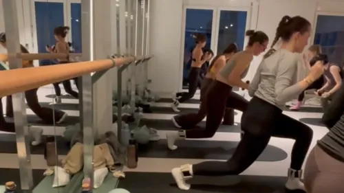 Menschen trainieren im Fitnessstudio mit Spiegeln.