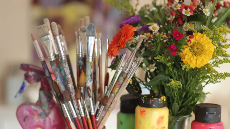 Paintbrushes and flowers on art table.