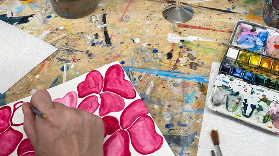 Person painting red shapes on messy table.