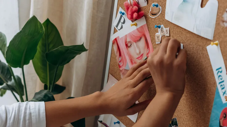 Hands pinning notes on a corkboard.