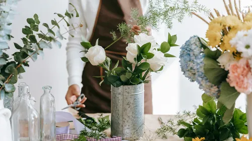 Person arrangiert Blumen auf Tisch.