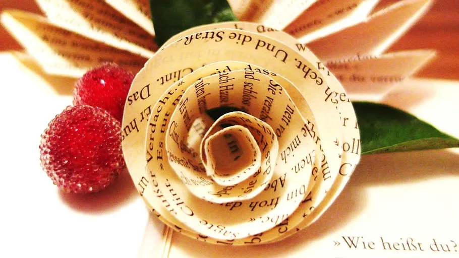 Paper rose and berries on a book.