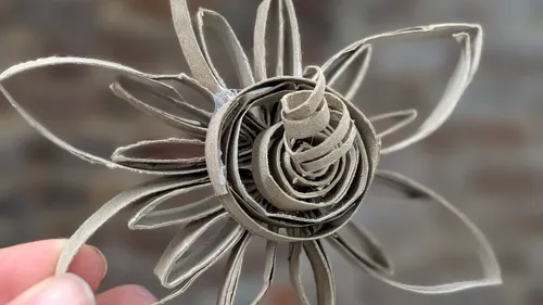 Hand hält Pappkarton-Papierblumenskulptur.