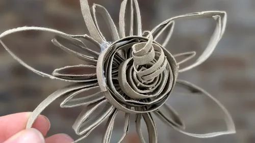 Hand hält Pappkarton-Papierblumenskulptur.