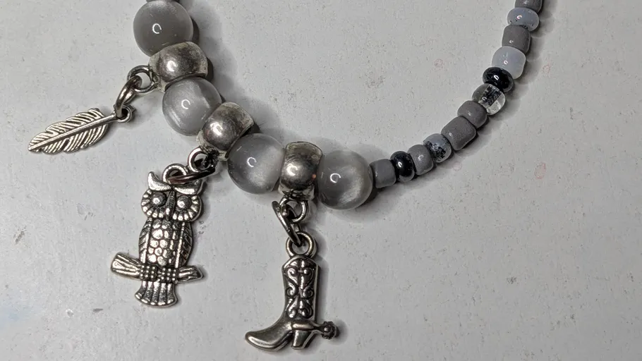 Beaded bracelet with owl, leaf, boot charms.