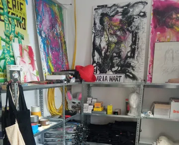 Art studio with colorful paintings on shelves.
