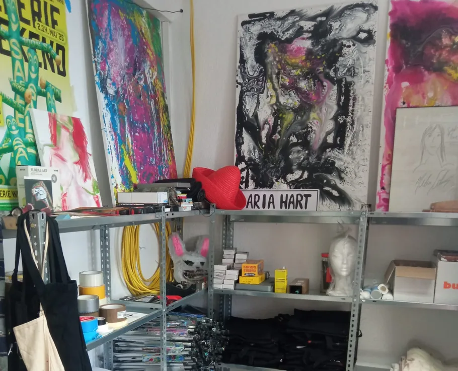 Kunststudio mit bunten Gemälden auf Regalen.
