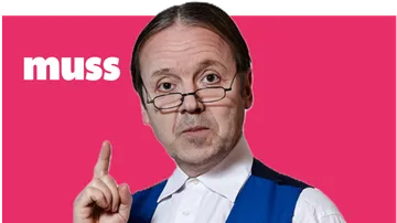 Man with glasses pointing against pink background.